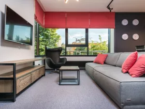 Modern office interior with sofa, red window shades, and television