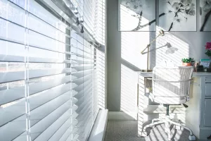 Image of a home office with white window blinds on the left side of the room